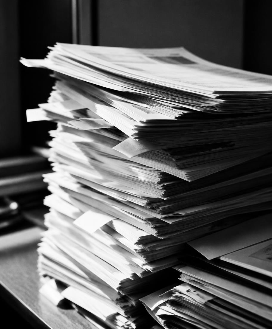A tall stack of printed HR paperwork on a desk